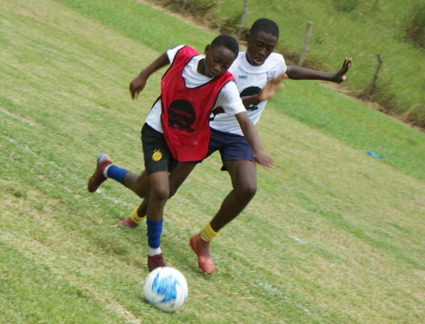 Two young boys playing soccer on a field.
