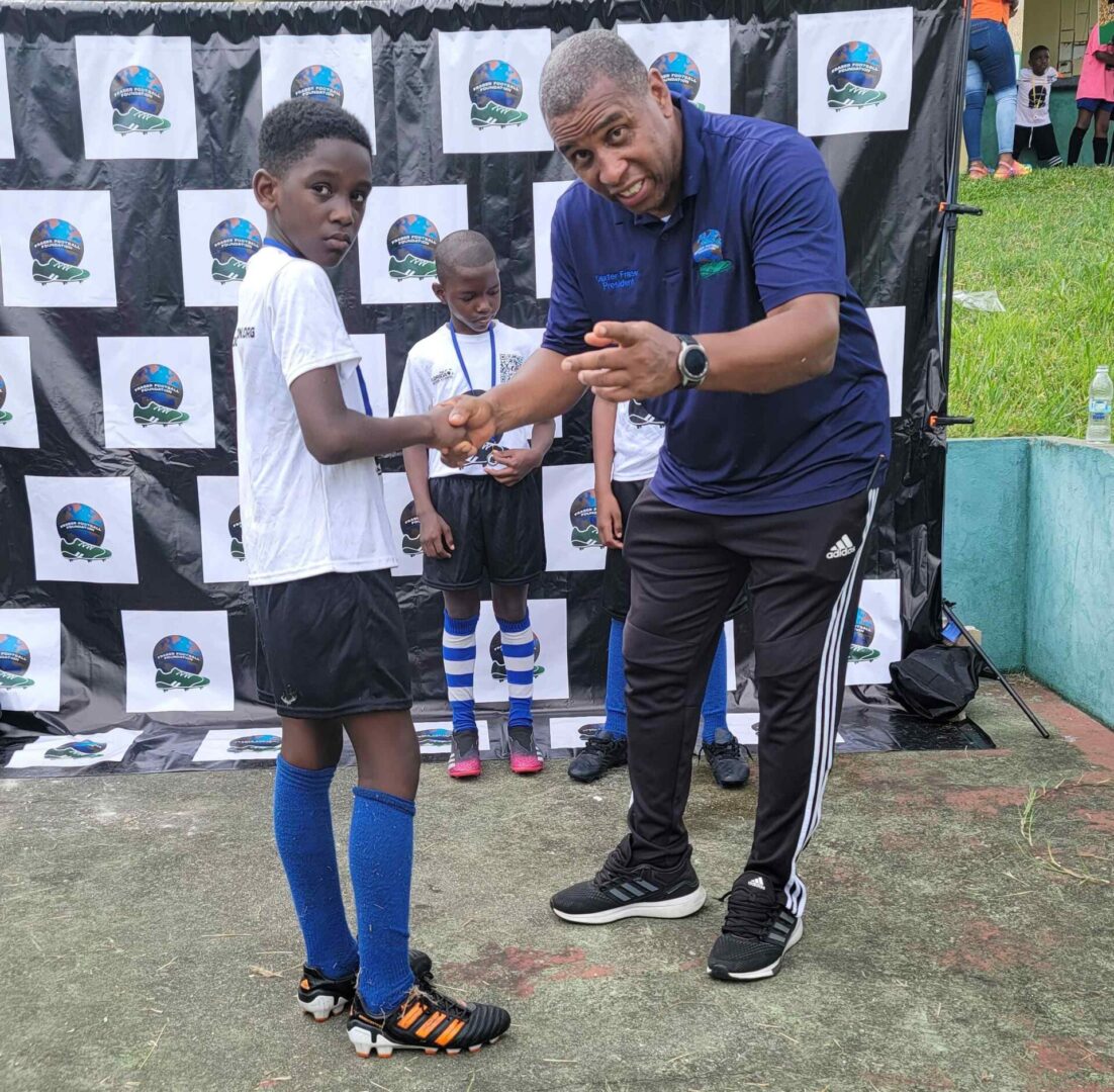 A man is helping another boy with his soccer shoes.