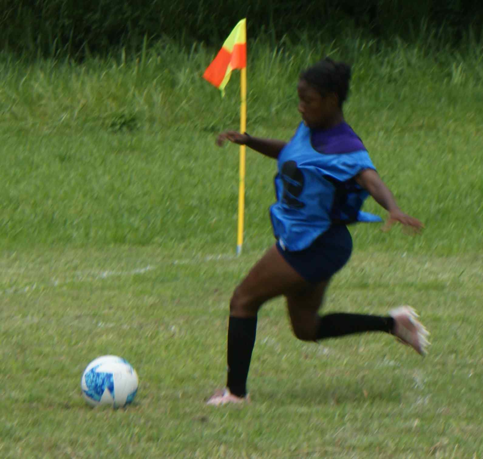 A girl running across the grass with a soccer ball.