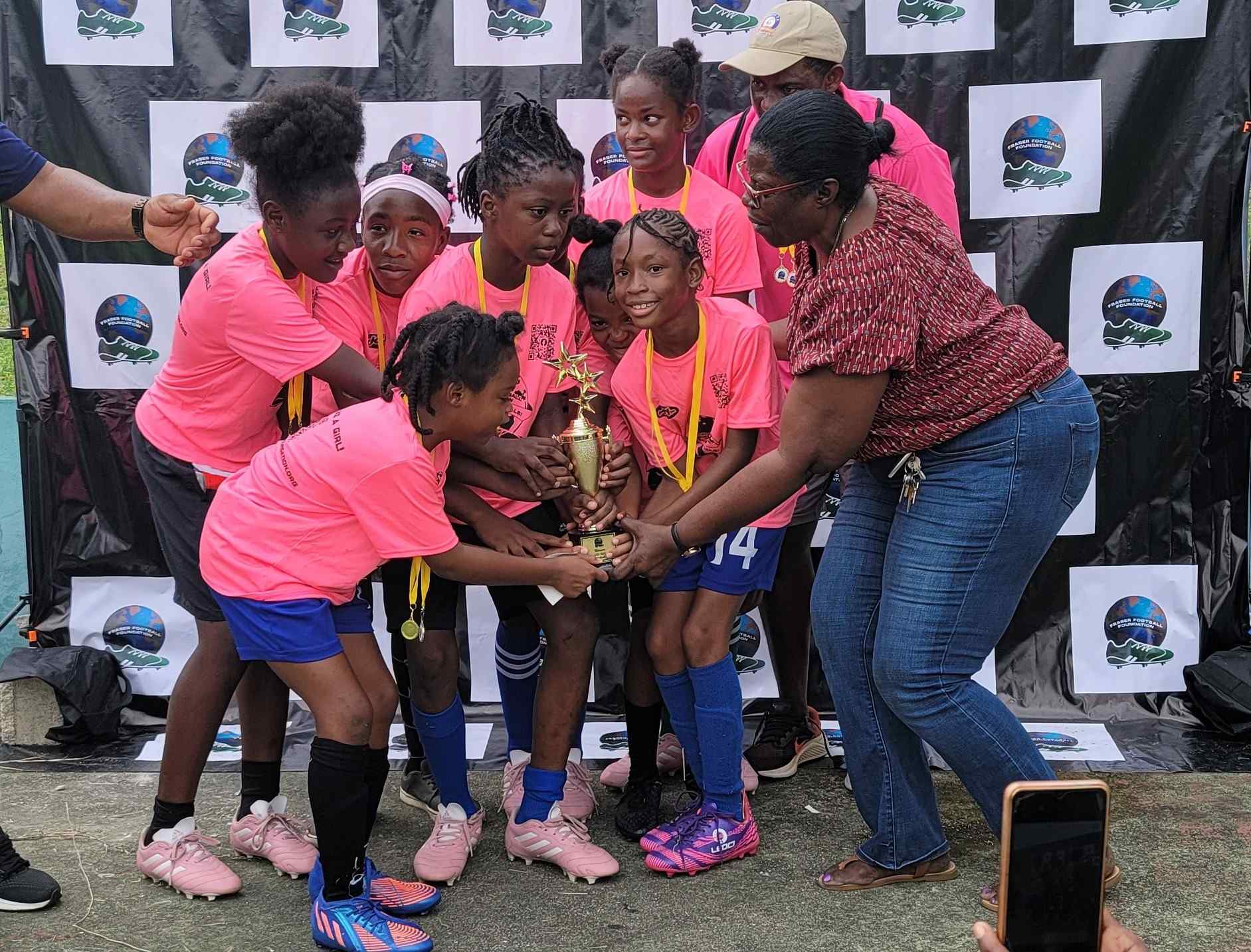 A group of girls holding onto a trophy